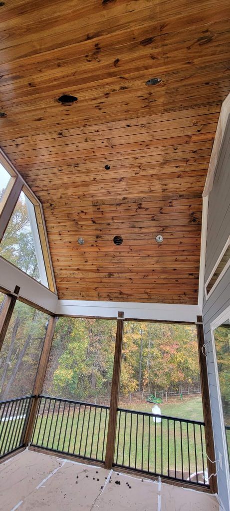 A Screened Porch With a Wooden Ceiling and a Railing