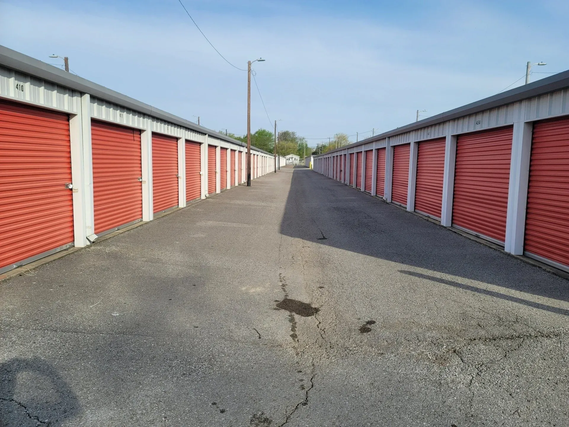 Rows of red storage units with a paved walkway in between.