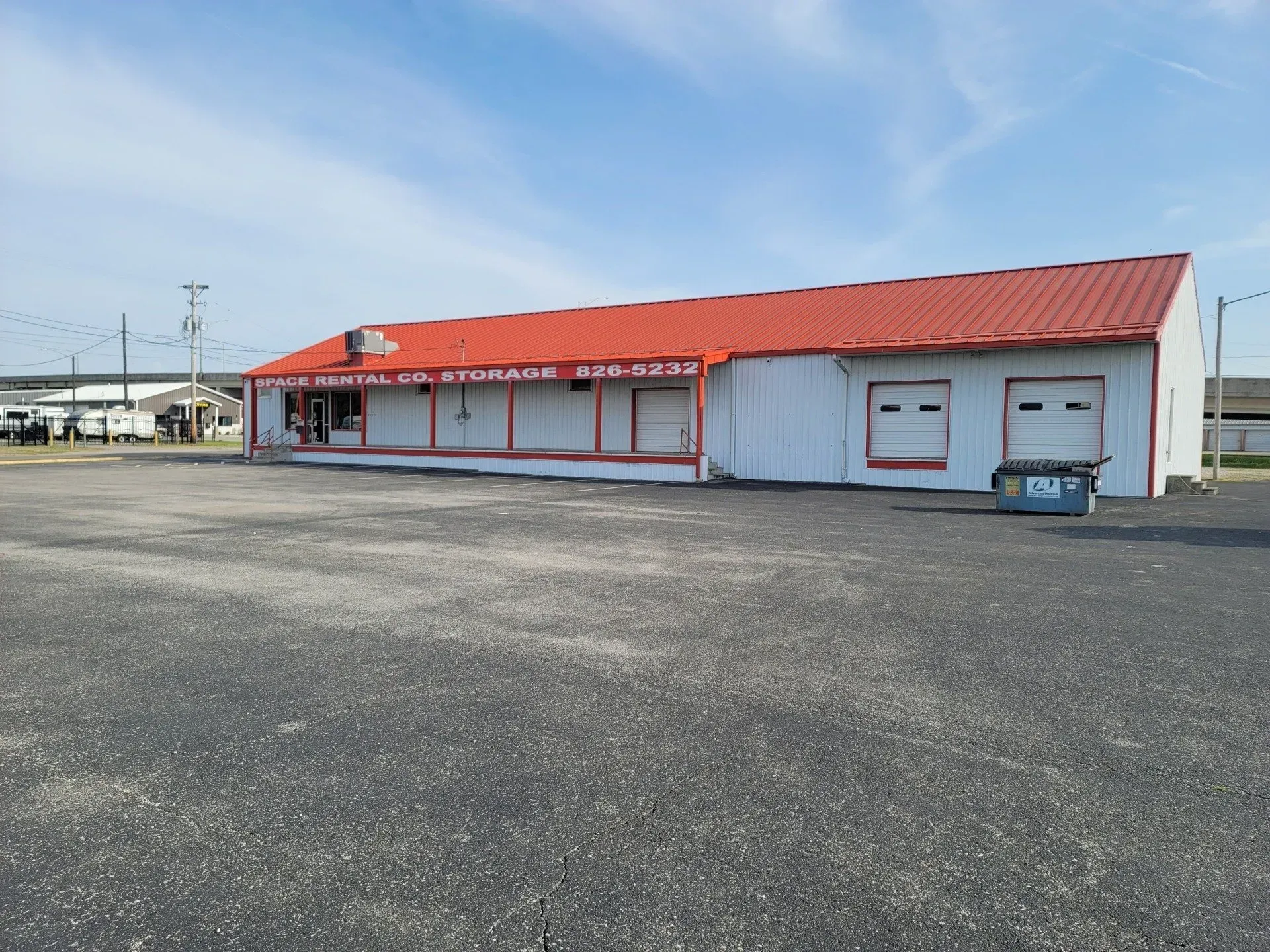 White commercial building with red roof and empty parking lot.