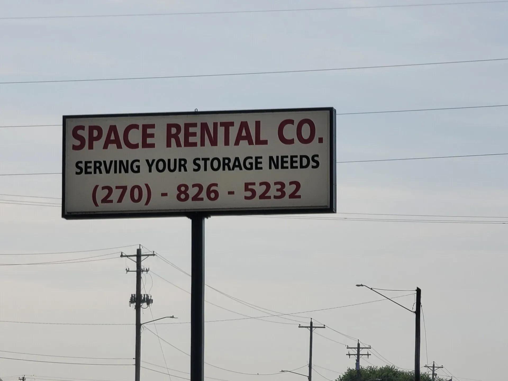 Sign for Space Rental Co., with phone number (270)-826-5232, under a cloudy sky.