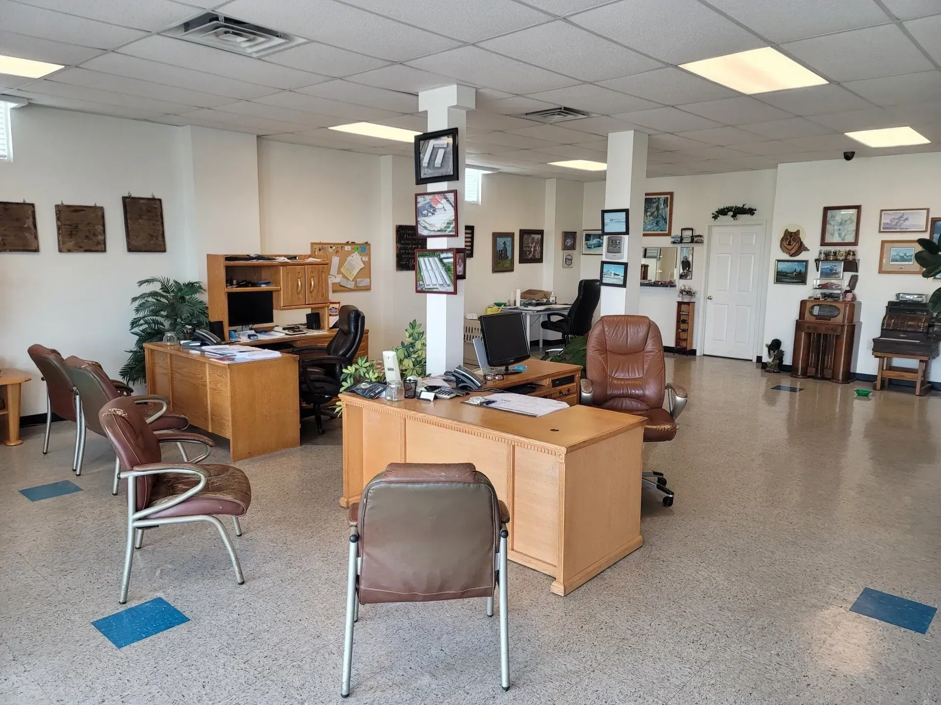 Office with light wood desks, brown leather chairs, and artwork on the walls.