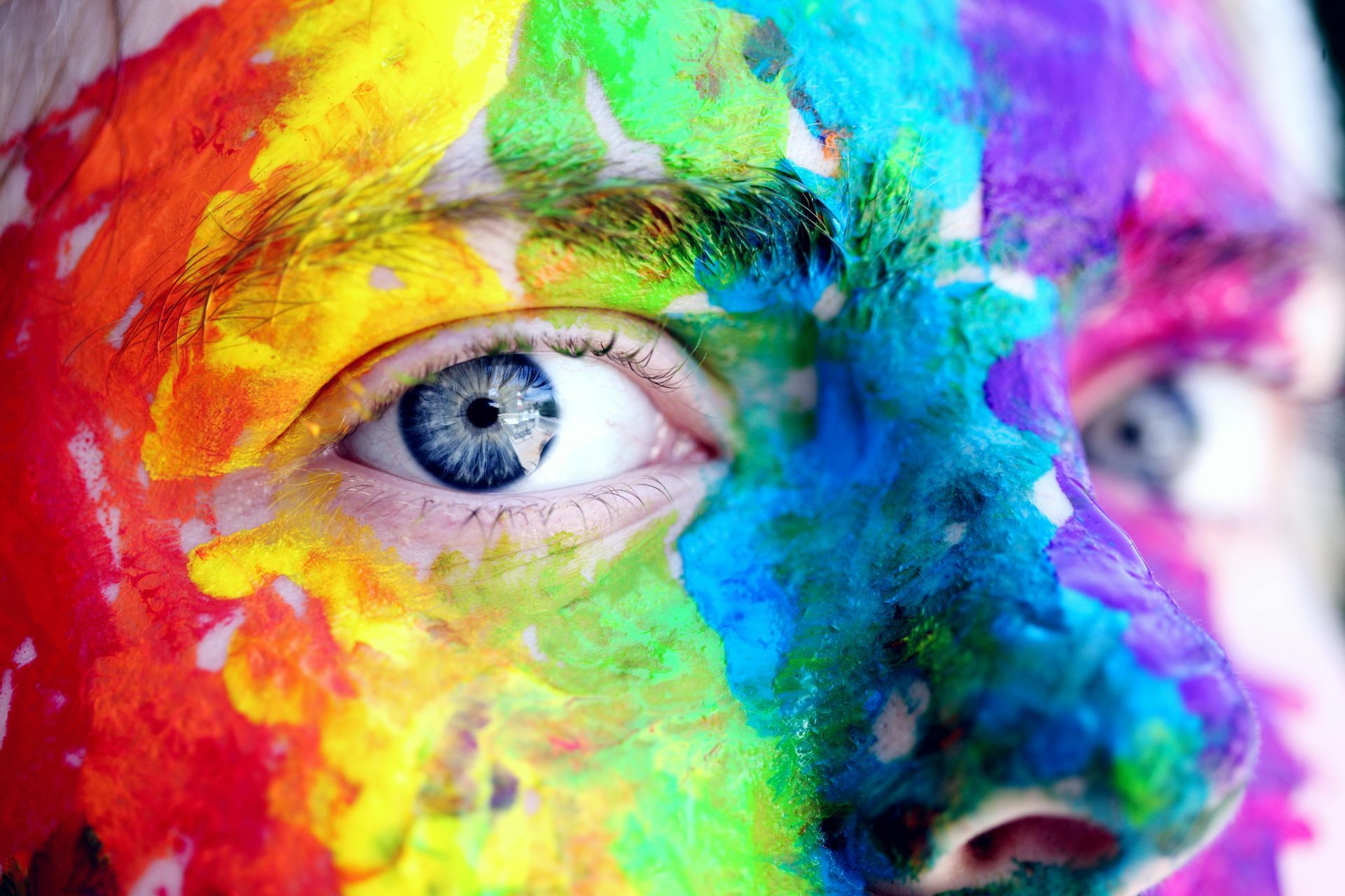 A close up of a person 's face with rainbow paint on it.