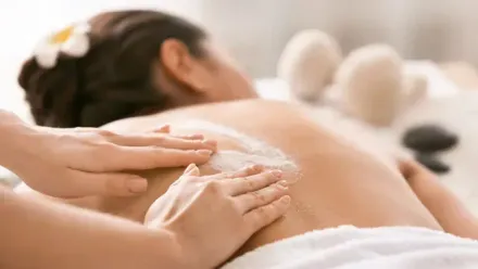 Person receiving a back treatment at a spa; hands applying cream.