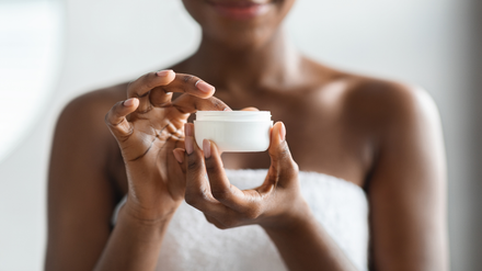 A woman is holding a jar of cream in her hands.