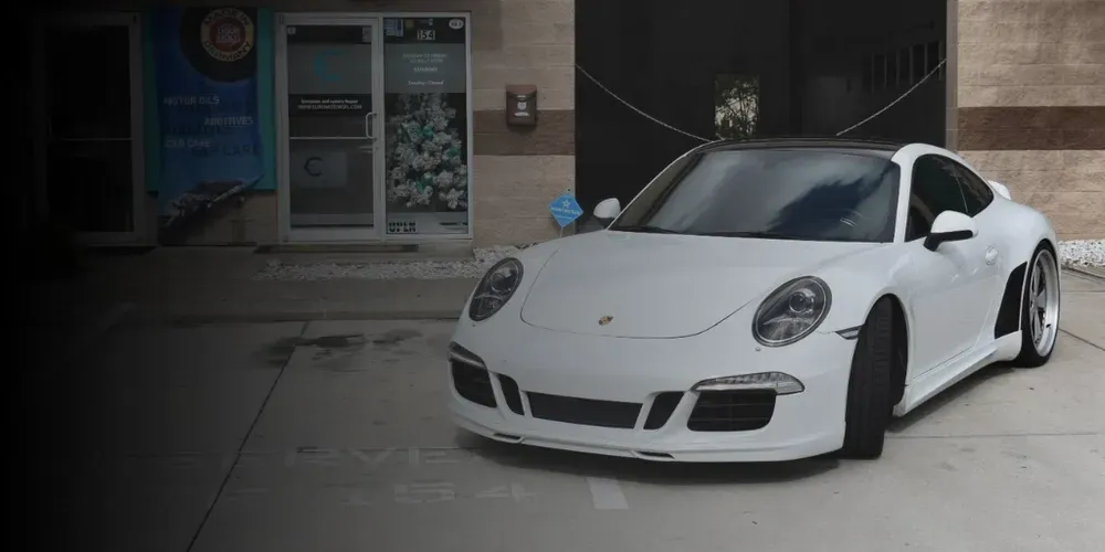 White sports car parked outside a building, front-left view