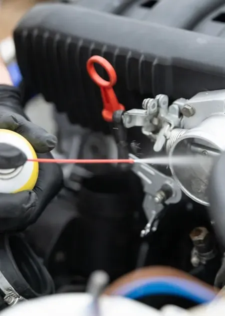 Close-up of a car engine with a red dipstick and a gloved hand measuring fluid