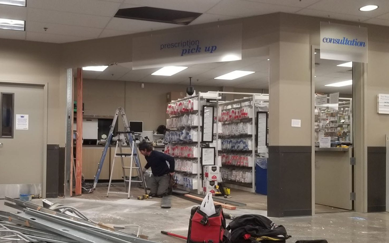 Workers installing store shelving in a retail space under renovation.