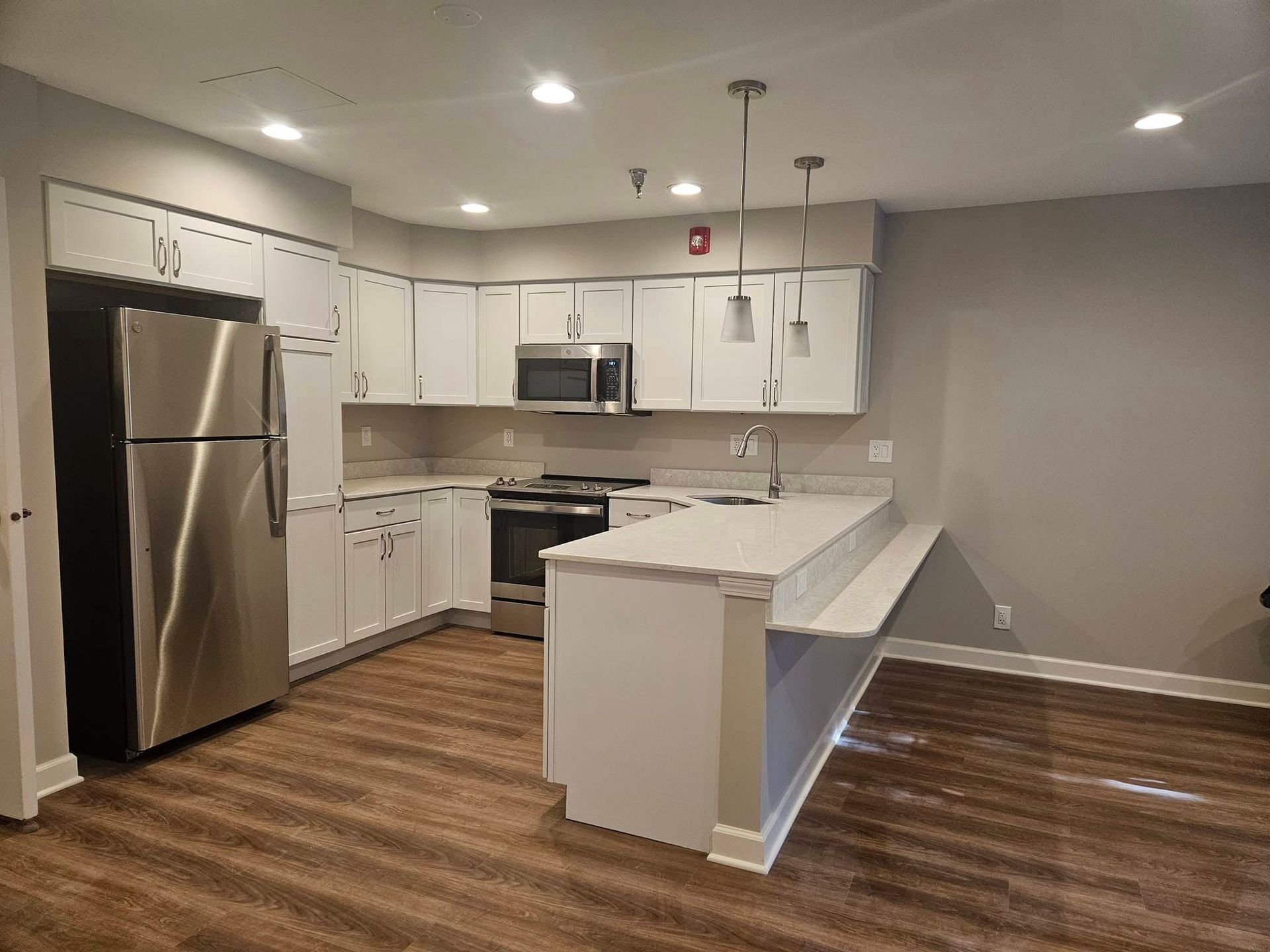 Modern kitchen with white cabinets, stainless appliances, wood floors, and a large white island