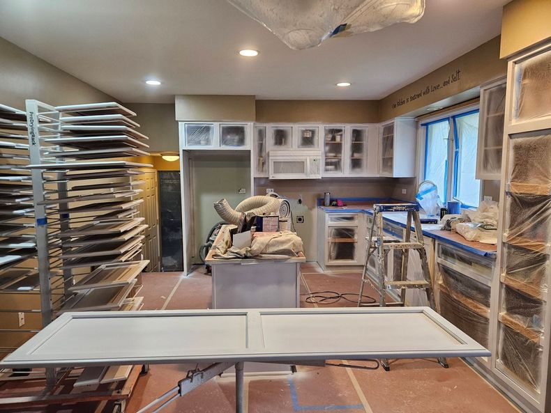 Commercial kitchen with stainless steel racks, prep tables, and equipment under warm ceiling lights