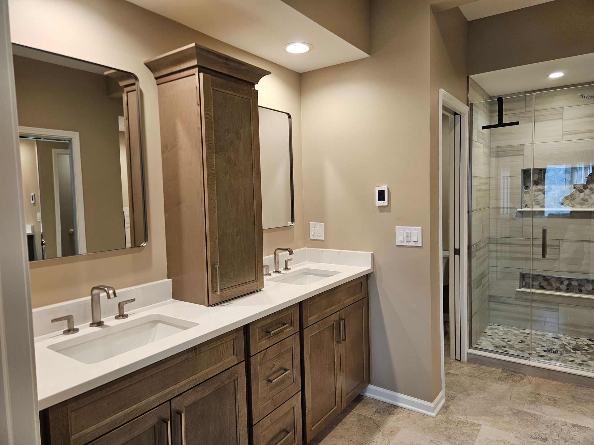Bathroom with double vanity, large mirror, and glass walk-in shower.