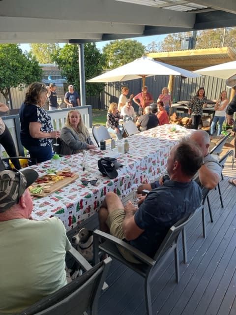 A Group Of People Are Sitting Around A Long Table — Tru Blu Catering In Sawtell, NSW