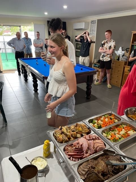 A Woman Is Standing In Front Of A Buffet Table With A Pool Table In The Background — Tru Blu Catering In Coffs Harbour, NSW