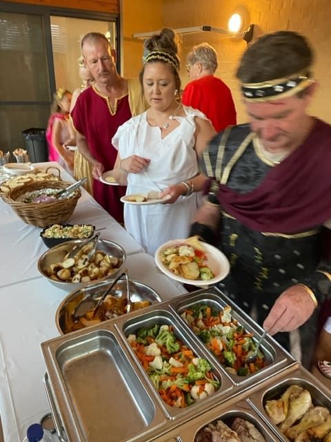 A Group Of People Are Standing Around A Buffet Table Eating Food — Tru Blu Catering In Coffs Harbour, NSW