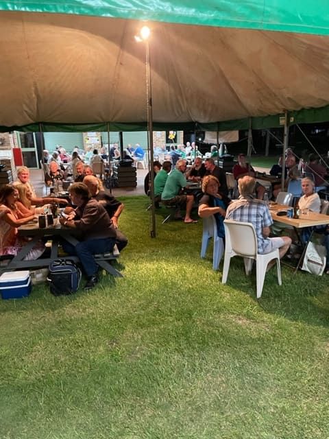 A Group Of People Are Sitting At Tables Under A Tent — Tru Blu Catering In Taree, NSW