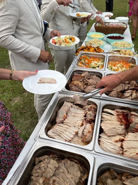 A Group Of People Are Standing Around A Buffet Table Eating Food — Tru Blu Catering In Wauchope, NSW