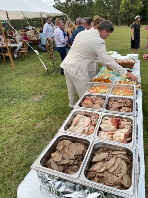 A Man Is Standing In Front Of A Buffet Table Filled With Food — Tru Blu Catering In Wauchope, NSW