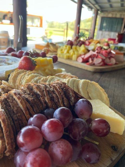 A Wooden Cutting Board With Grapes Cheese And Crackers On It — Tru Blu Catering In Port Macquarie, NSW