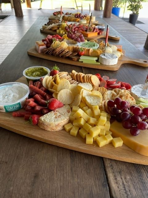 A Wooden Cutting Board Filled With Cheese And Fruit — Tru Blu Catering In Kempsey, NSW