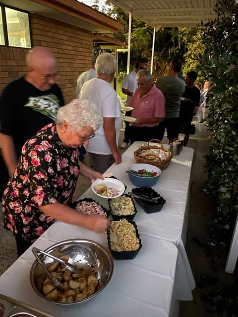 A Group Of People Are Standing Around A Table Eating Food — Tru Blu Catering In Port Macquarie, NSW