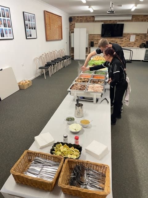 People Standing Around A Long Table Filled With Food — Tru Blu Catering In Port Macquarie, NSW