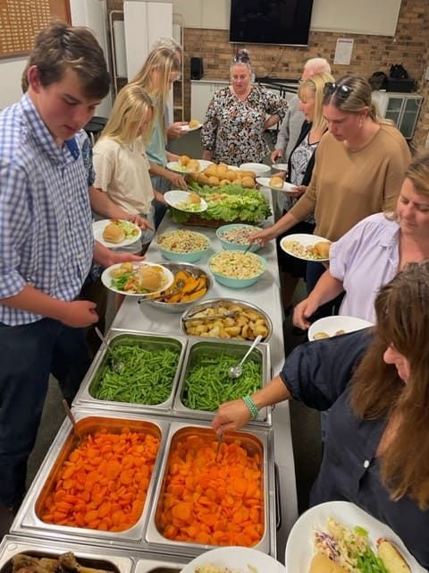 A Group Of People Are Standing Around A Table Filled With Food — Tru Blu Catering In Port Macquarie, NSW