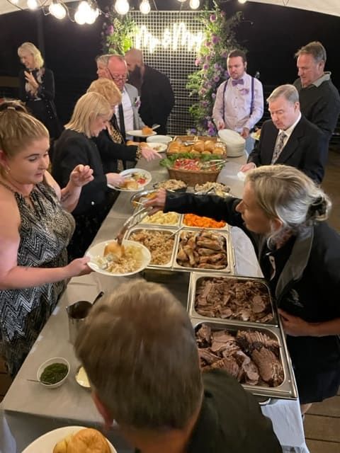 A Group Of People Are Standing Around A Table Eating Food — Tru Blu Catering In Port Macquarie, NSW