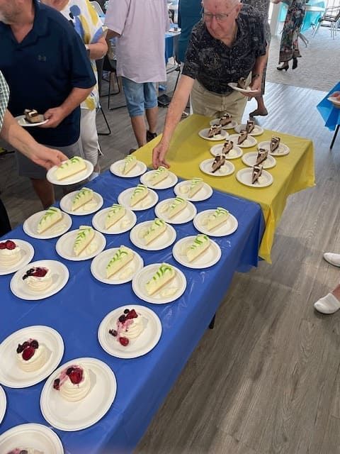 A Group Of People Standing Around A Table With Plates Of Food On It — Tru Blu Catering In Port Macquarie, NSW