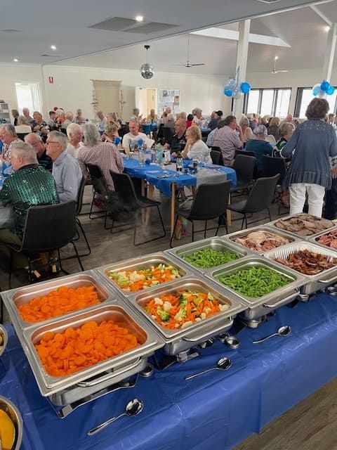 A Large Group Of People Are Sitting At Tables At A Buffet Table— Tru Blu Catering In Port Macquarie, NSW