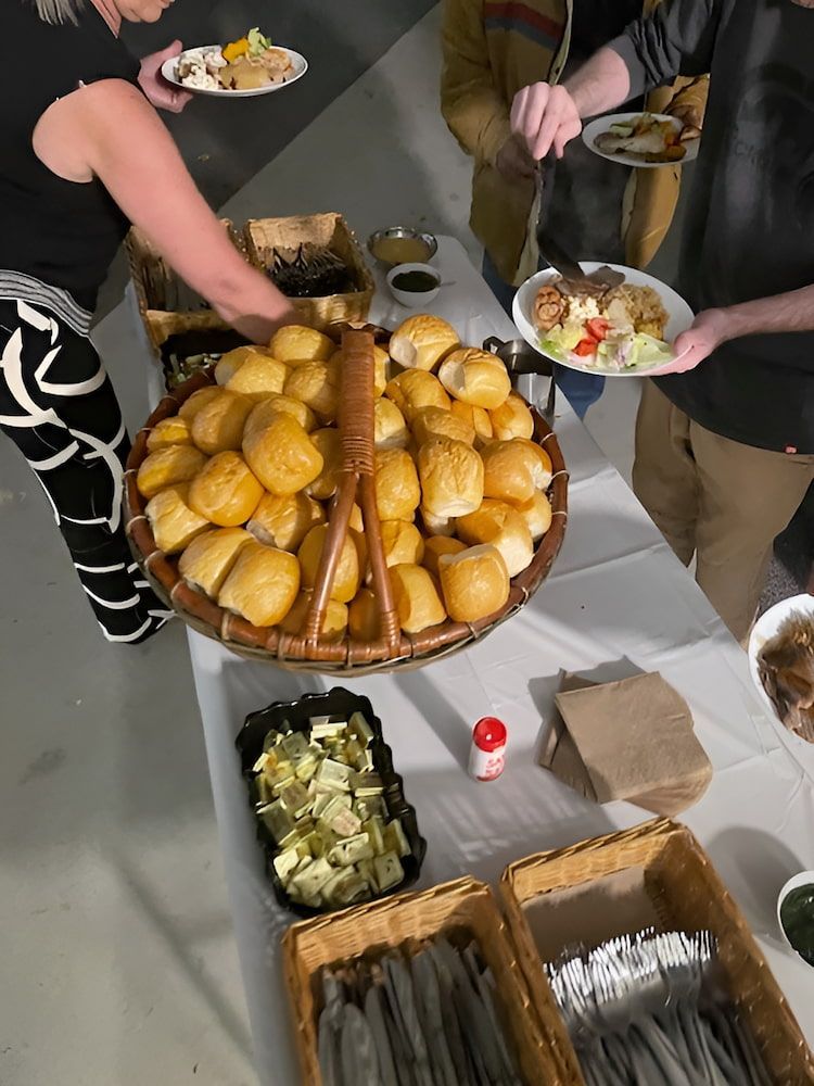 A Group Of People Are Standing Around A Table Holding Plates Of Food — Tru Blu Catering In Port Macquarie, NSW