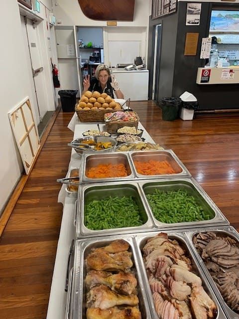 A Woman Is Sitting At A Table With A Variety Of Food On It — Tru Blu Catering In Port Macquarie, NSW
