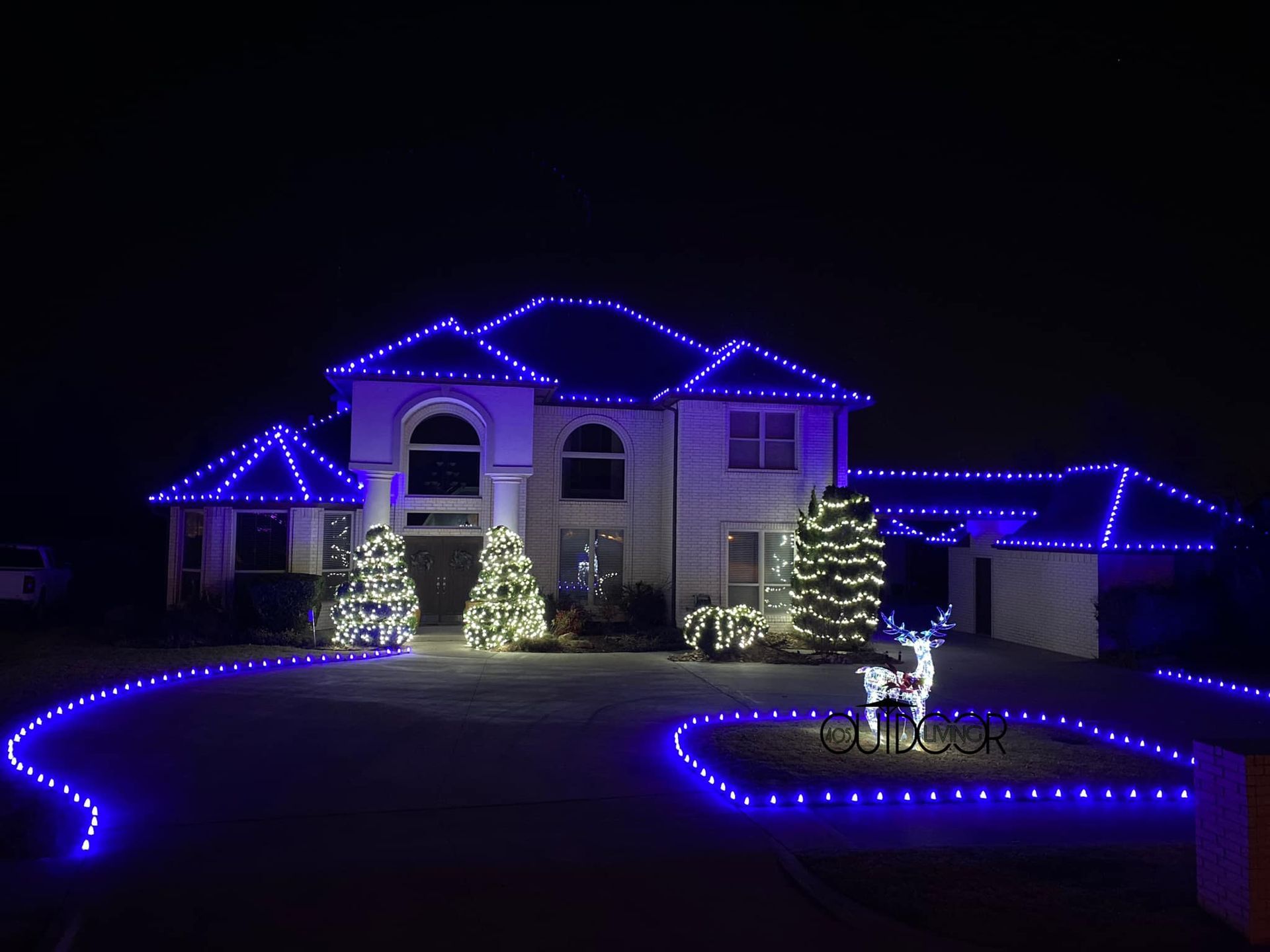 House decorated for Christmas with blue lights outlining the roof and yard.