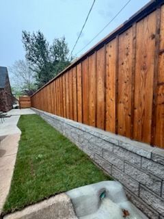 A wooden fence surrounds a lush green yard.