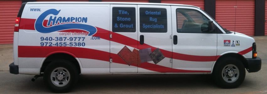 White van with Champion Tile, Stone & Carpet logo. Red and blue accents, parked by storage units.
