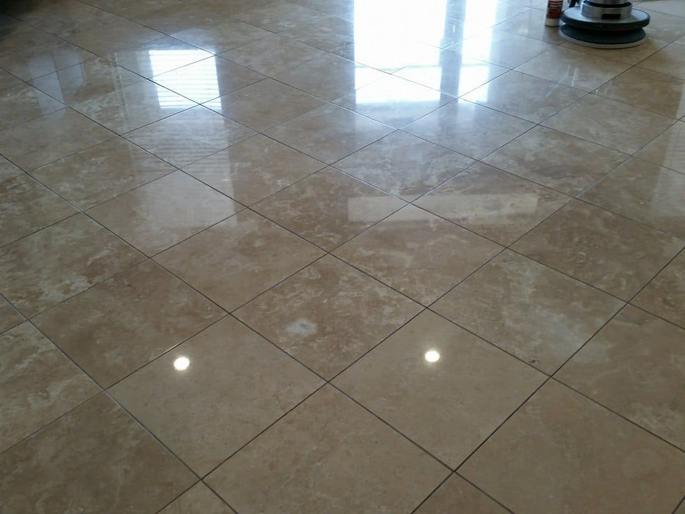 Polished beige tile floor with diamond pattern, reflecting light from a window and a floor polisher.