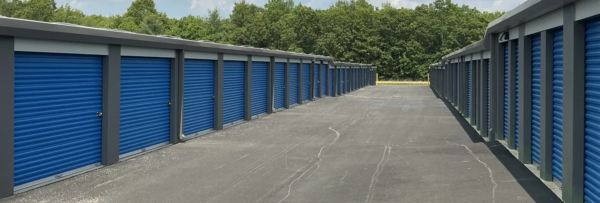 Storage units in a long hallway, with closed roll-up doors on the left and an open end.