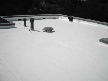 White rooftop with vents and pipes under a dark sky