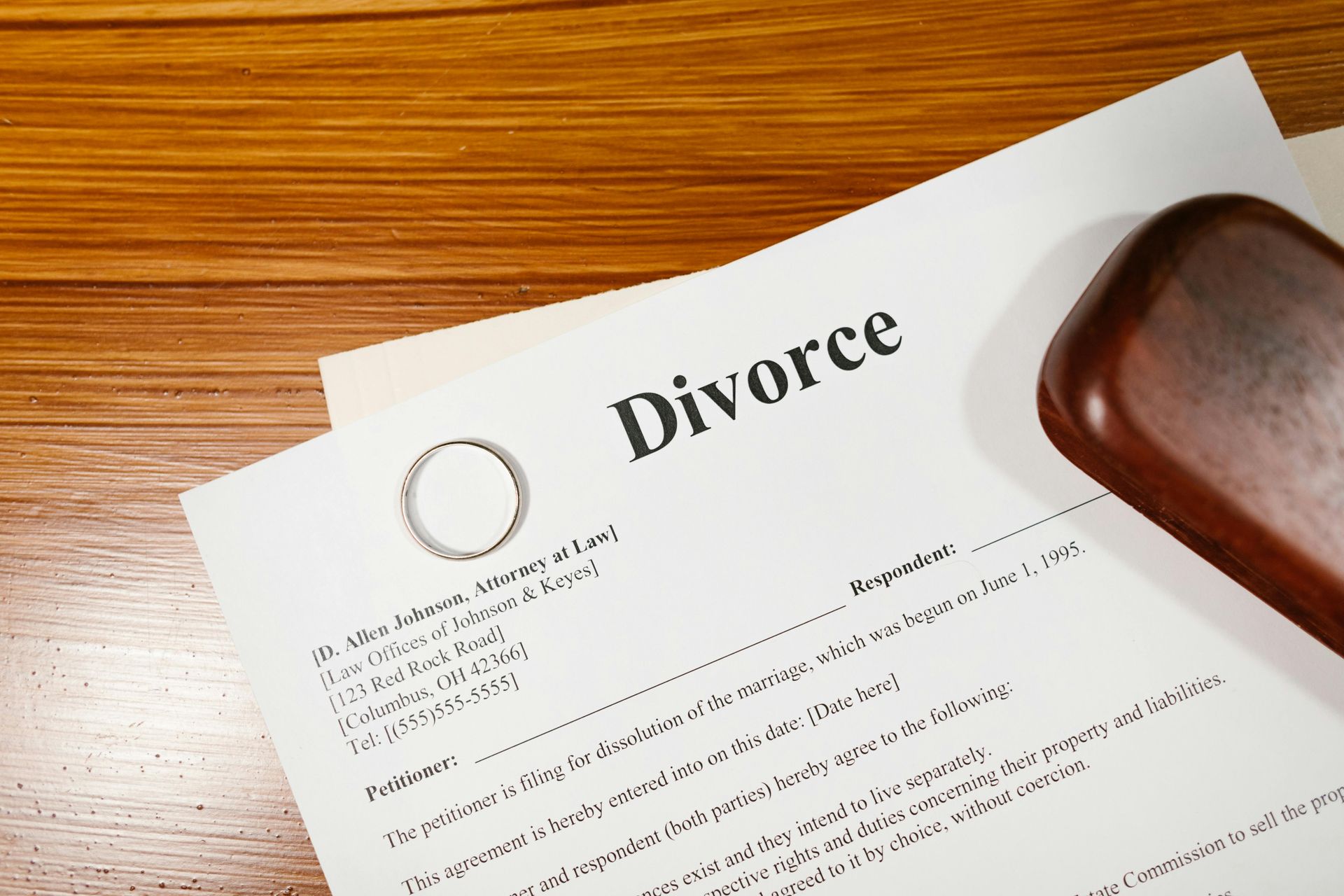 Divorce papers on a wooden desk with a pen and stamp-like object nearby