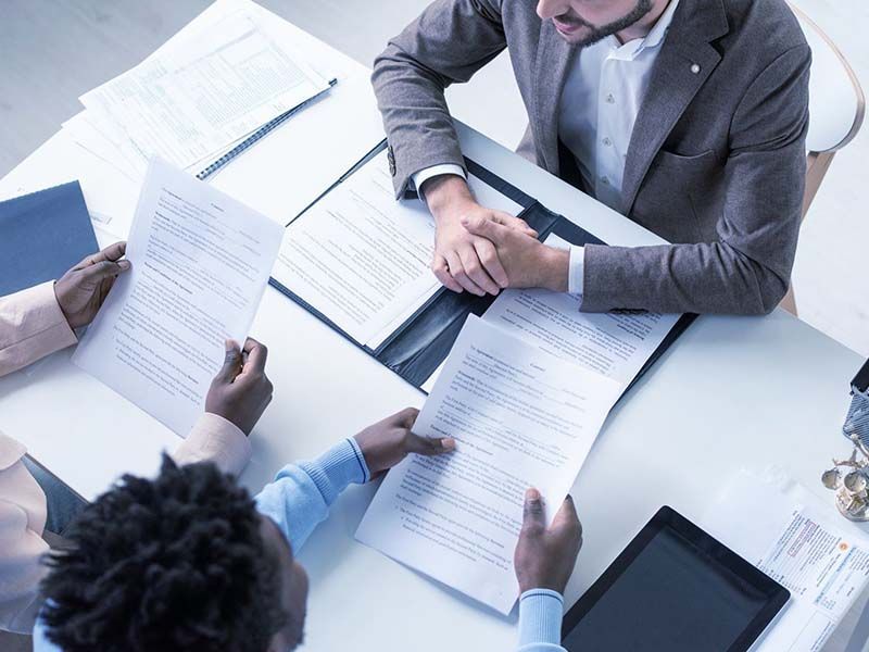 A group of people are sitting at a table looking at papers.