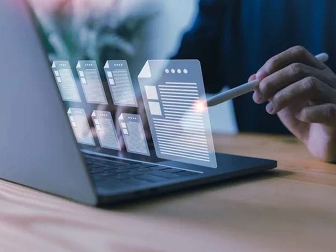A person is holding a pen in front of a laptop computer.