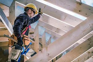 A construction worker is working on a wooden structure.