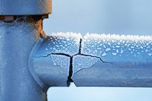 A close up of a cracked pipe with snow on it.