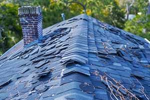 A close up of a roof with a chimney and trees in the background.