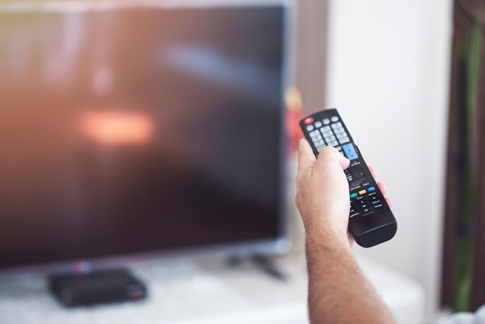 Hand Holding a TV Remote Pointed at a Flat-screen Television — MATV Systems Australia Pty Ltd in Wickham, NSW