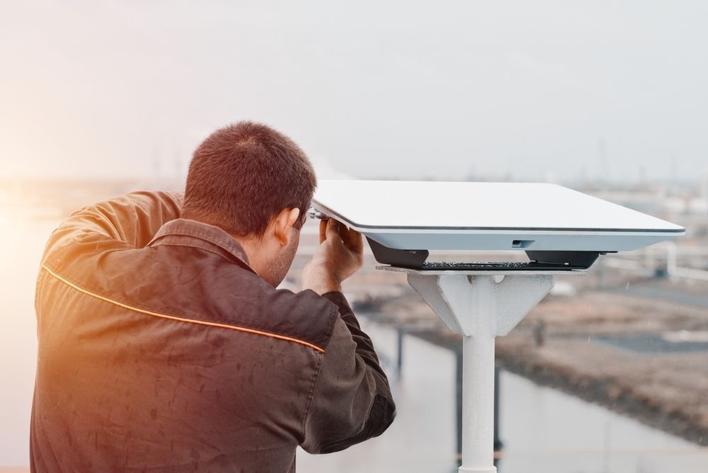 Person Adjusting a Starlink Mounted on a Pole Outdoors at Sunset — MATV Systems Australia Pty Ltd in Wickham, NSW