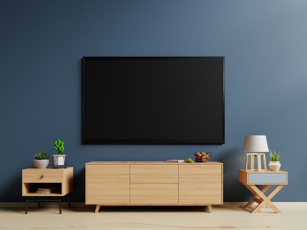 Minimal living room with blue wall, wall-mounted TV, wooden console, plant, lamp, and side table — MATV Systems Australia Pty Ltd in Wickham, NSW