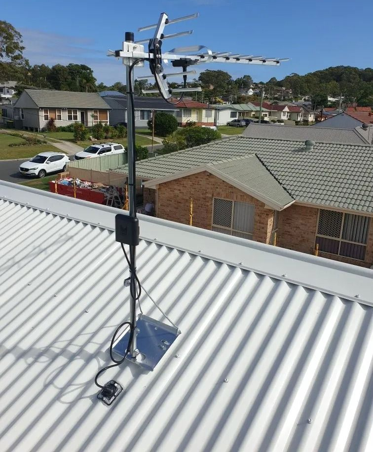 TV antenna mounted on a rooftop with suburban houses and blue sky in the background — MATV Systems Australia Pty Ltd in Wickham, NSW