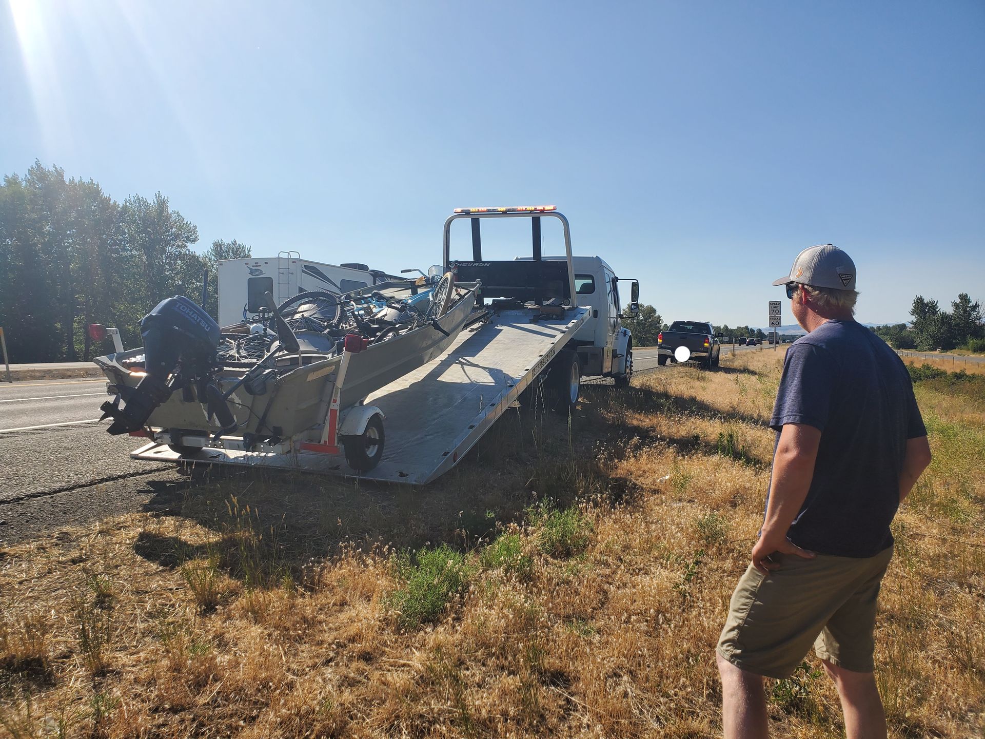 A man standing in front of a tow truck with a boat on it