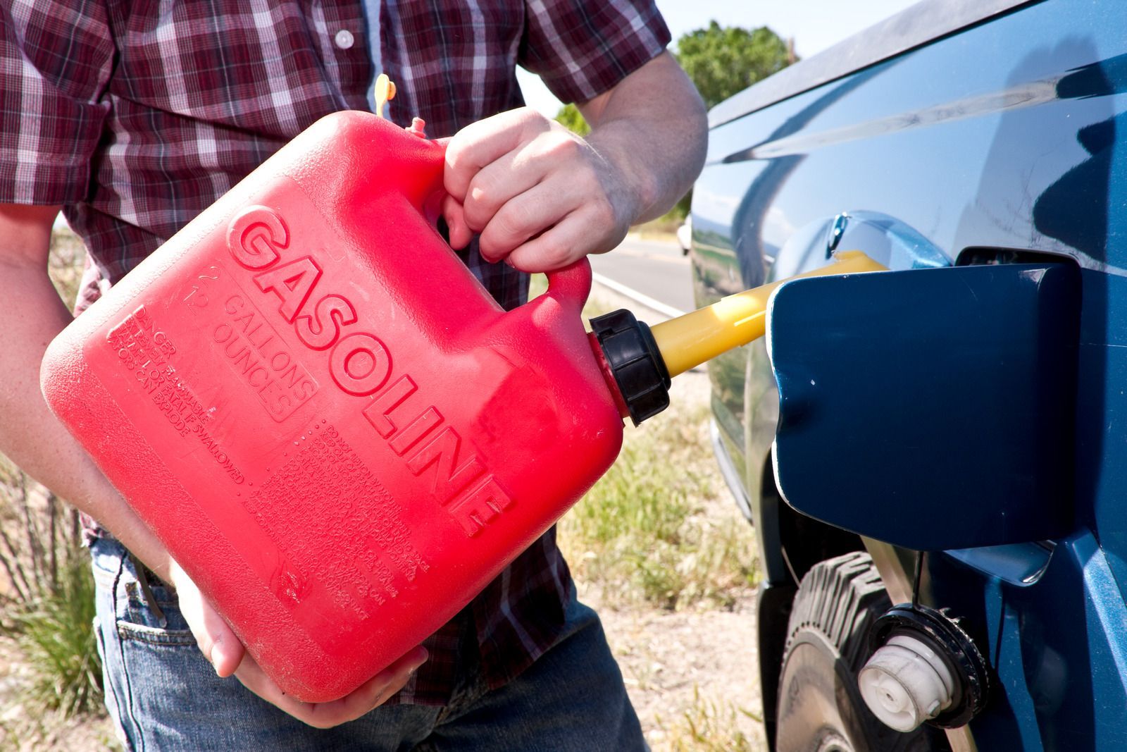 A man is pouring gasoline into a blue truck