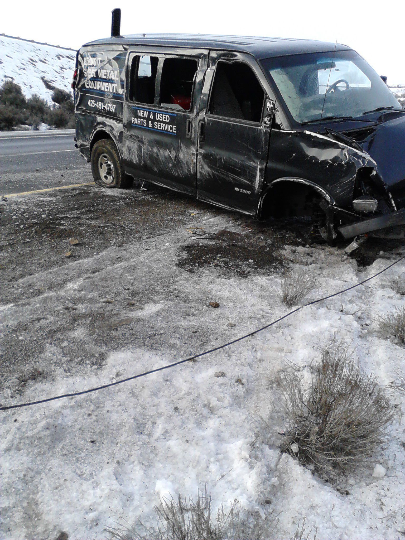 A black van is sitting in the snow next to a black car.