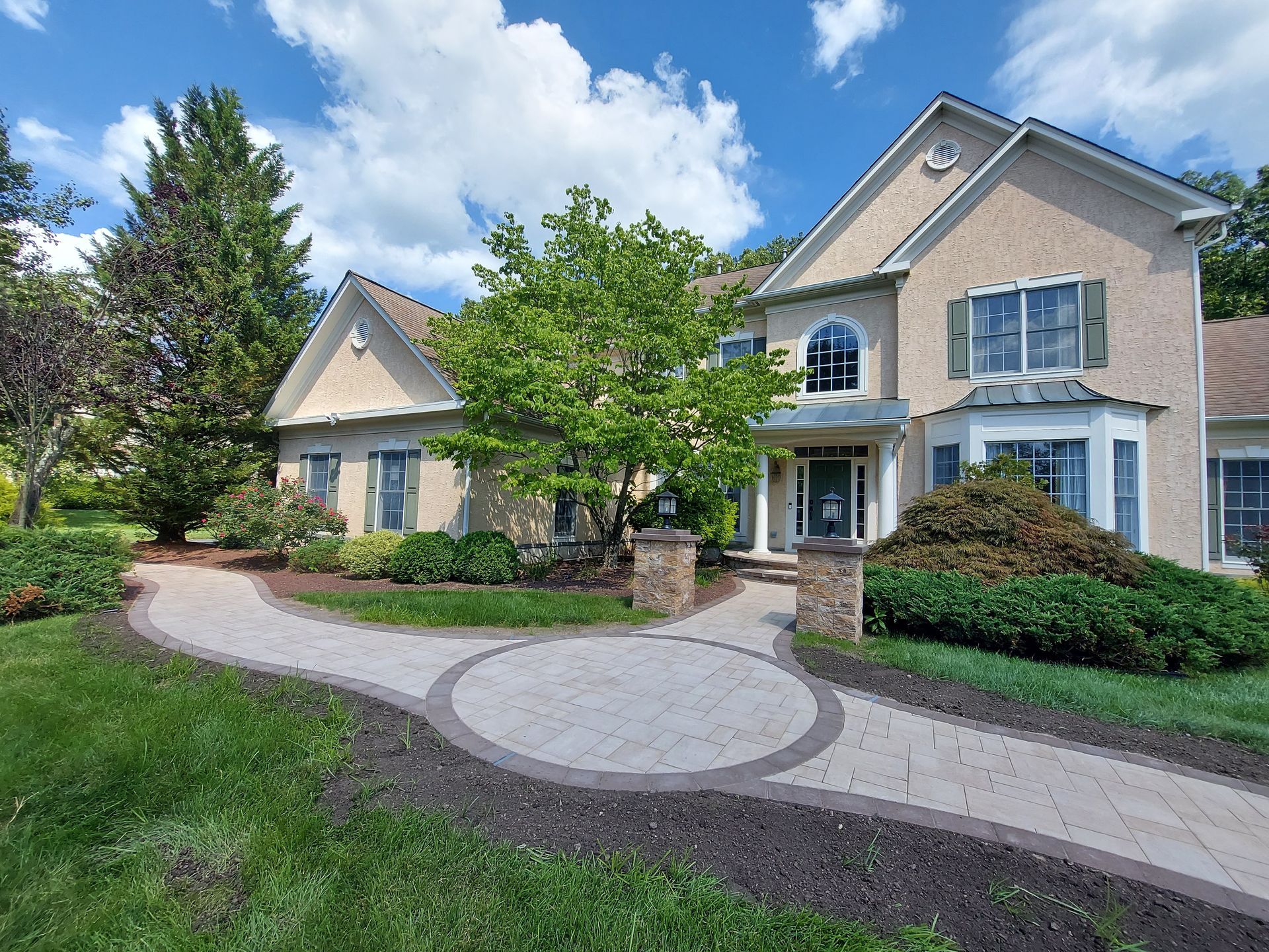 A yellow Caterpillar skid steer and a red dump truck with a load of gravel sit next to a house under a clear blue sky. A yellow Caterpillar skid steer and a red dump truck with a load of gravel sit next to a house under a clear blue sky.
